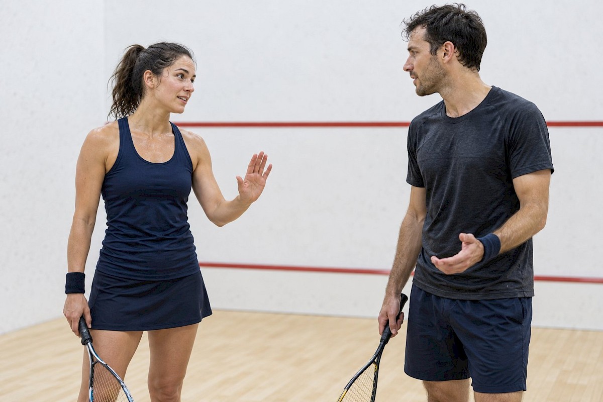Two squash players pausing safely to discuss an interference decision